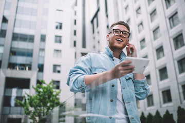 Happy man using tablet walking in street