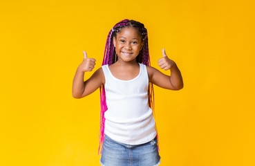 Pretty little african american girl gesturing thumbs up and smiling - Powered by Adobe