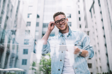 Excited guy calling friend using tablet in modern city