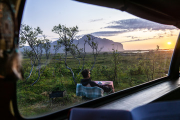 the man outside the window looks at the sunset