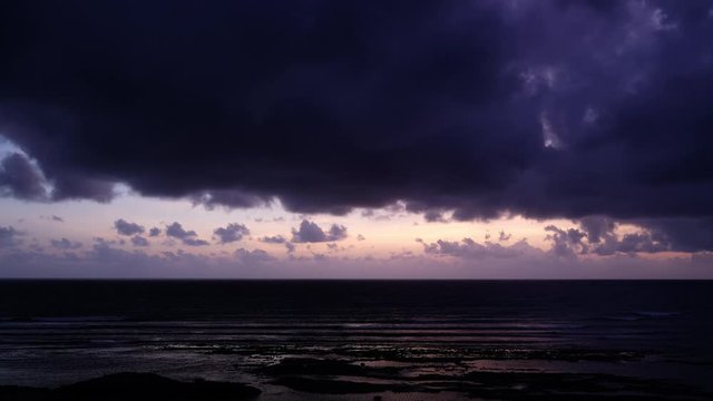 Stock 4k: Time lapse, timelapse of sunrise sky on the beach. Royalty high-quality free stock time lapse footage of sun rays emerging though the dark storm clouds background. Dramatic sunset sky cloud