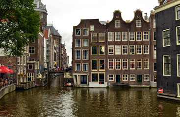 Naklejka premium Amsterdam, Netherlands. August 2019. Typical view of the historic center: bridges over the canals are chosen by tourists to take a break to observe the particular landscape.