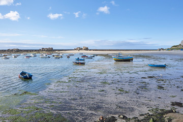 Coastline at low tide, sand and seaweed, boats in the shallow water, peaceful and silent mood, summer feeling