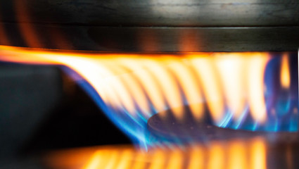 A Macro Image of a Blurry Blue and Yellow Flames on Gas Stove Burner.