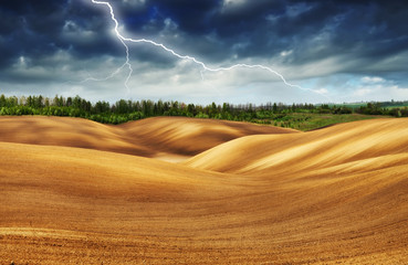 Fototapeta premium thunderstorm in the field. huge lightning over a hilly field. bad weather in the field