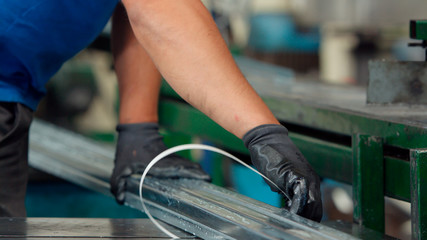 Worker packing aluminum profiles at the warehouse of metal products.