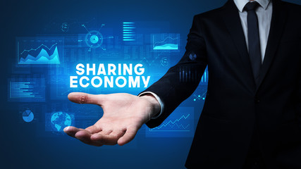 Hand of Businessman holding SHARING ECONOMY inscription, business success concept