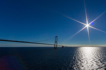 Oresund bridge with blue ocean, sky, sun and light reflexes