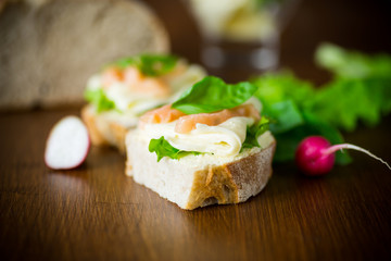 sandwich with cheese, salad leaves and red fish on a wooden