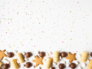 Sweet festive pastry border with chocolate, waffles, cookies, marshmallows and pastry topping on a white background.