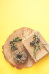 Zero waste gift ideas. Giftbox bowed with cord and olive branch on wooden background and copyspace.