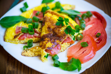 fried omelet from homemade organic eggs with tomatoes and green onions