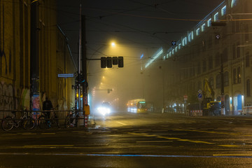 Naklejka premium Foggy Cross Road in a city at night, cross roads, wet and foggy cross road, traffic lights, tram station at night, foggy crossroad in Berlin Oberschöneweide