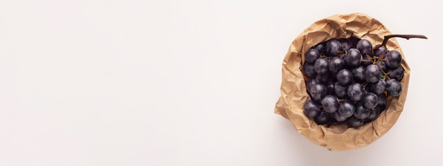 Blue grape branch inside eco paper bag isolated on white