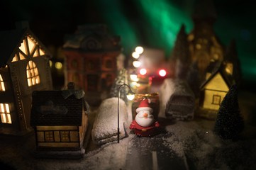 New Year miniature house in the snow at night with fir tree. Holiday concept. Selective focus