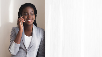 Afro Businesswoman Talking On Smartphone Near Window In Office
