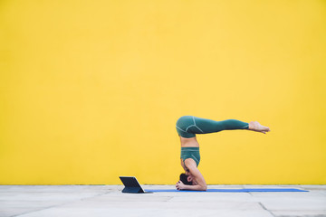 Sporty woman stretching on yoga mat on yellow background