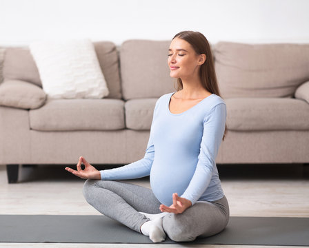 Relaxed young pregnant girl meditating on the floor