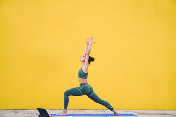 Fit woman meditating in yoga posture with arms raised - obrazy, fototapety, plakaty