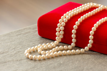 Beautiful natural pearl necklace laid on red velvet jewelry box.