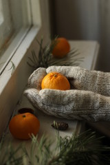 hands in mittens and tangerine