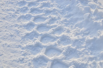 Wheel tread on white snow. The trail from the tread of truck wheel in the snowу road in winter time. Car tire tread imprint background, texture