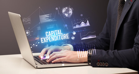 Businessman working on laptop with CAPITAL EXPENDITURE inscription, new business concept