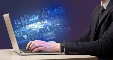 Businessman working on laptop with ENGINEERING SCIENCE inscription, cyber technology concept