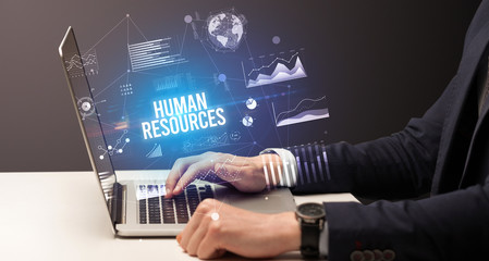 Businessman working on laptop with HUMAN RESOURCES inscription, new business concept