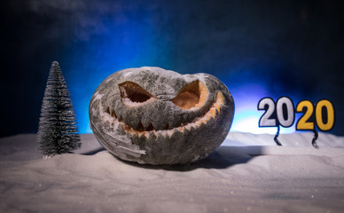 Christmas New Year or Halloween Celebrate Background with Little Christmas Tree on Blurred Bokeh Snow Background with horror pumpkin