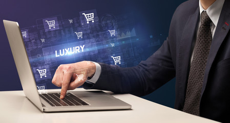 Businessman working on laptop with LUXURY inscription, online shopping concept