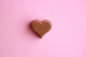 Chocolate bonbon with heart shape in color background