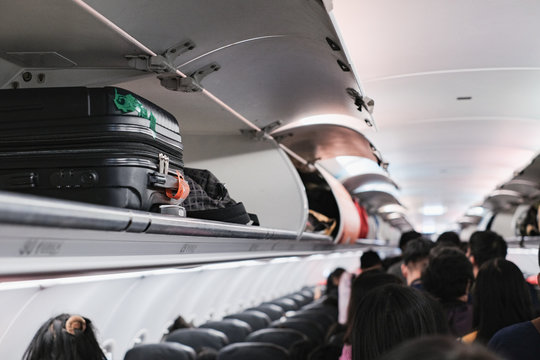 overhead locker on airplane,Passenger put cabin bag cabin on the top shelf. Travel concept