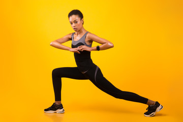Fototapeta na wymiar Black Girl Doing Deep Lunge Exercise Stretching Legs In Studio