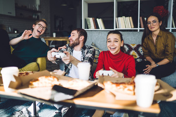Enthusiastic mates playing on console while relaxing at home