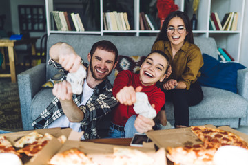Enthusiastic mates playing on gamepad in domicile