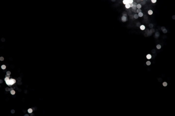 Abstract bokeh made from silver glitter on black background