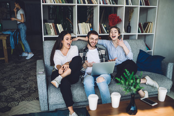 Group of young hipsters laughing and sitting on couch