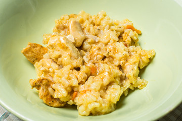 Cooked asian rice pilaf in green plate on the kitchen table.