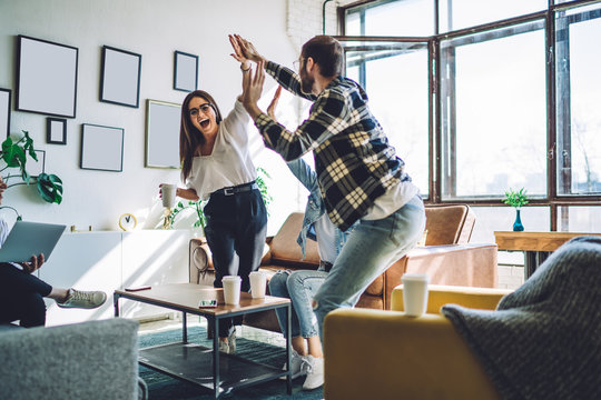 Excited Friends Giving High Five While Standing In Room