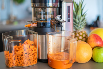 Making fruit juice with juicer machine in home kitchen, healthy eating lifestyle concept