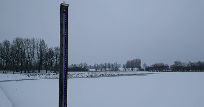 Normaal Amsterdams Peil (NAP), Amsterdam Ordinance Level, a vertical level meter in flooded river landscape + pan winter scenery