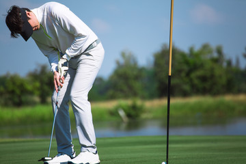 Golfer playing golf in the evening golf course, on sun set evening time. Man playing golf on a golf course in the sun.