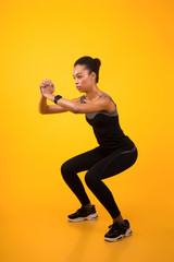 Fototapeta na wymiar African American Woman Doing Deep Squat Exercise Over Yellow Background