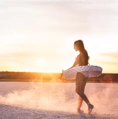 Fotobehang Tender young ballerina dancer in a snow-white tutu dress and white pointe shoes on a salty dried lake. Fantastic landscape and a girl  ballerina © Ann Stryzhekin