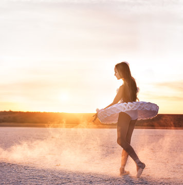 Tender young ballerina dancer in a snow-white tutu dress and white pointe shoes on a salty dried lake. Fantastic landscape and a girl  ballerina