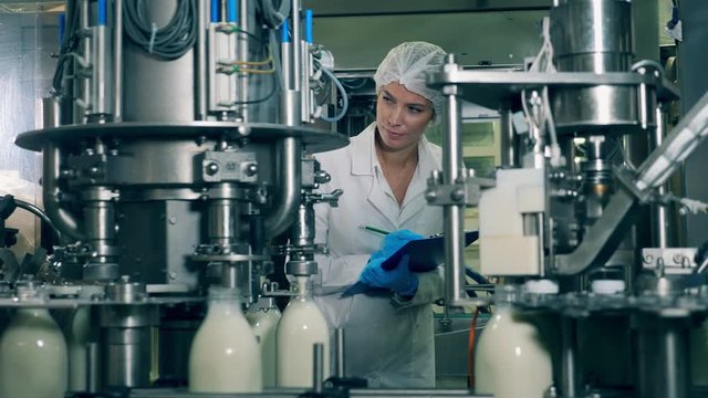 Dairy factory unit at work with a female employee observing it