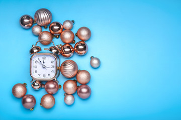 Alarm clock with Christmas balls on color background