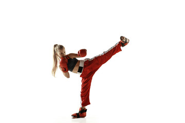 Young female kickboxing fighter training isolated on white background. Caucasian blonde girl in red sportswear practicing in martial arts. Concept of sport, healthy lifestyle, motion, action, youth.