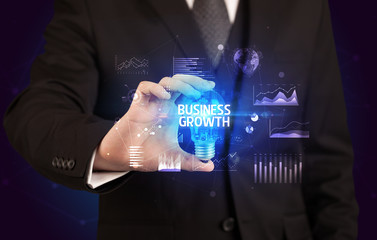 Businessman holding lightbulb with BUSINESS GROWTH inscription, Business idea concept